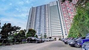A parking lot with multiple cars and a tall residential building in the background. - Collection O near Terminal Pulo Gebang formerly Sentra Timur - Tower Sapphire (Jakarta)