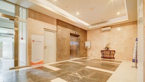 A modern lobby with a marble floor, an elevator, a reception desk, and a glass door entrance. - Collection O near Terminal Pulo Gebang formerly Sentra Timur - Tower Sapphire (Jakarta)