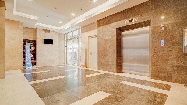 A spacious lobby with a marble floor, a glass door leading to another area, and an elevator. - Collection O near Terminal Pulo Gebang formerly Sentra Timur - Tower Sapphire (Jakarta)