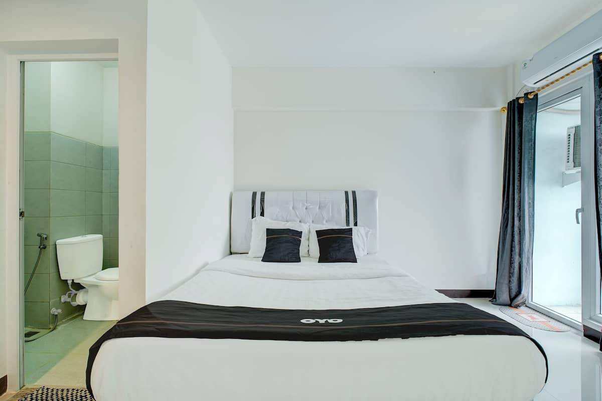 Habitació d'hotel amb un llit, un vàter i una zona de dutxa.