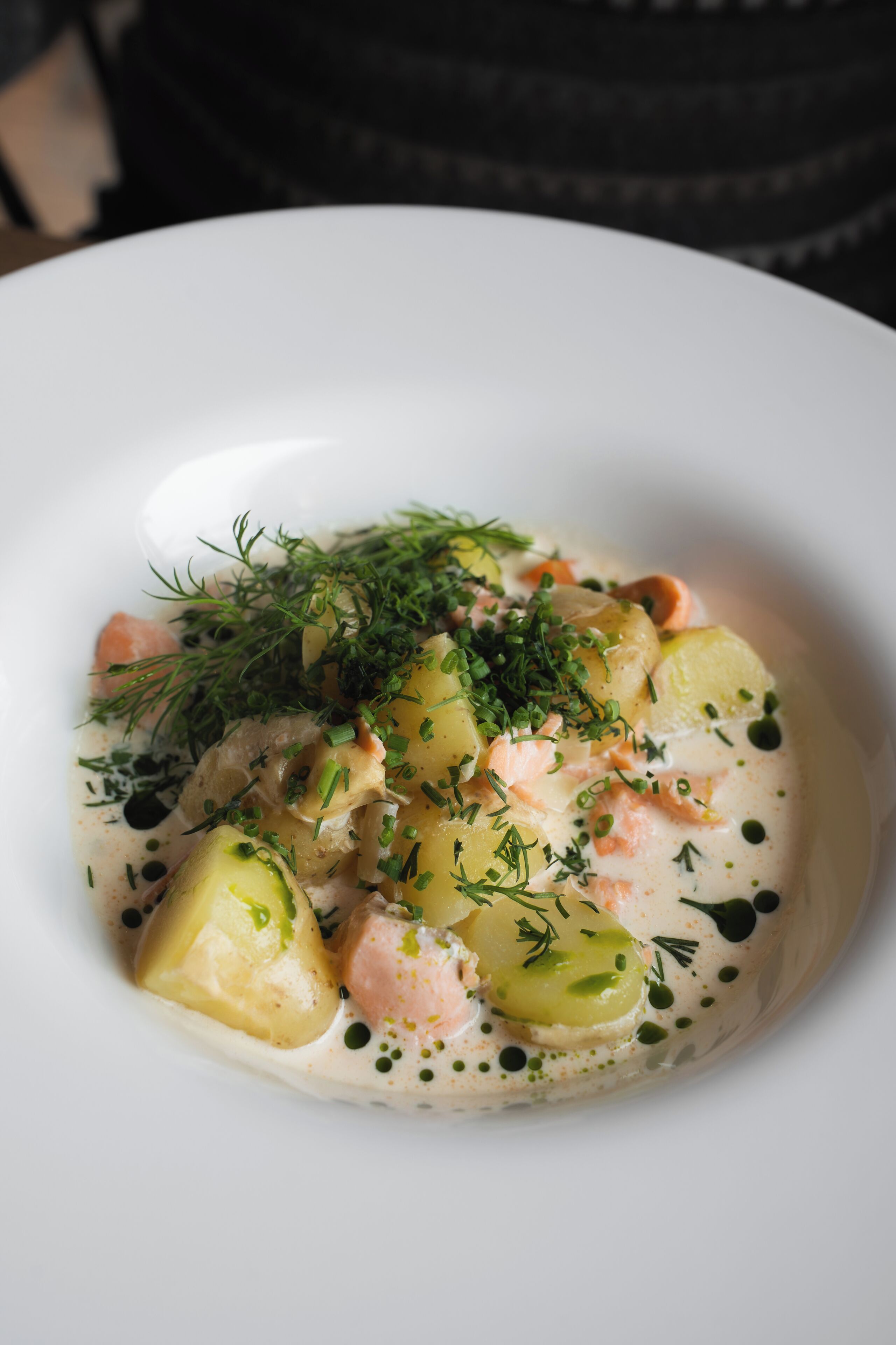 Une assiette blanche contenant un plat crémeux composé de pommes de terre, de carottes et d’herbes aromatiques.