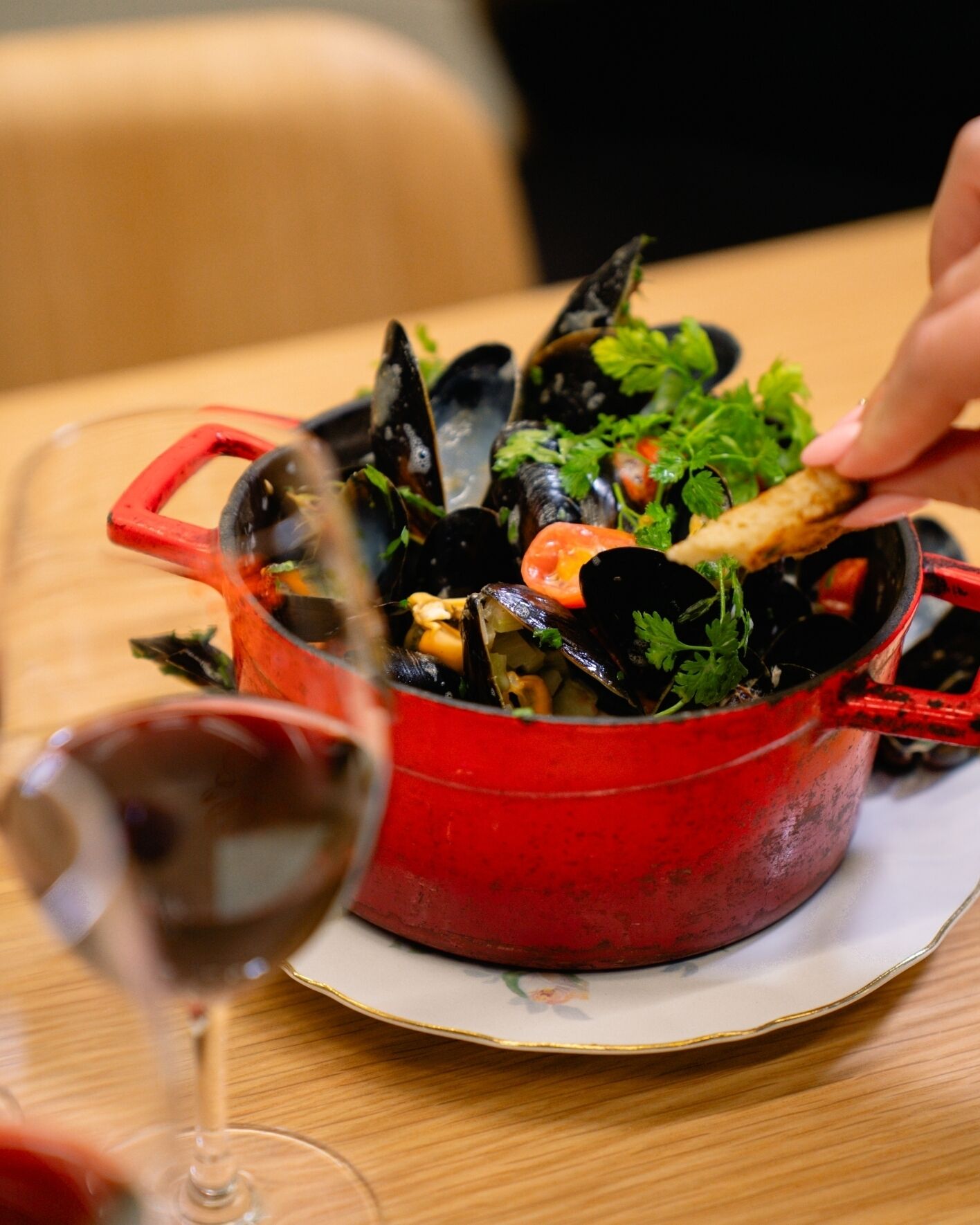 Una olla roja llena de mejillones y verduras sobre una mesa.