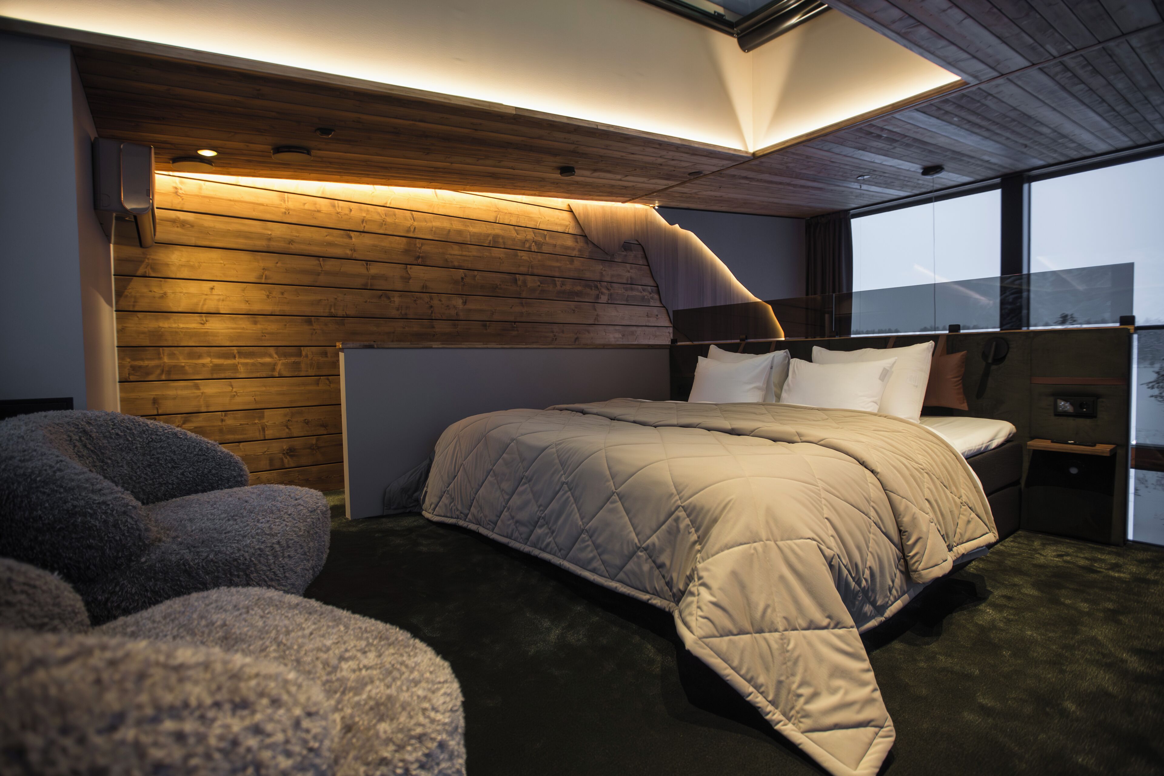 Un dormitorio con literas, techo de madera, una ventana grande y una mesita de noche pequeña.