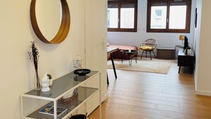 Una sala de estar moderna con una mesa consola de cristal, un espejo grande y una cesta de mimbre.