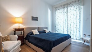 A bedroom with a bed, bedside table, lamp, and a window with curtains. - Ca' Orso Marino (Venice)