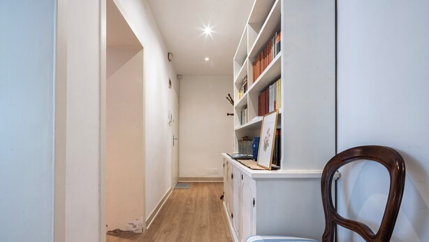 A hallway with a wooden floor, a white wall, and a bookshelf with books and a framed picture. - Ca' Orso Marino (Venice)