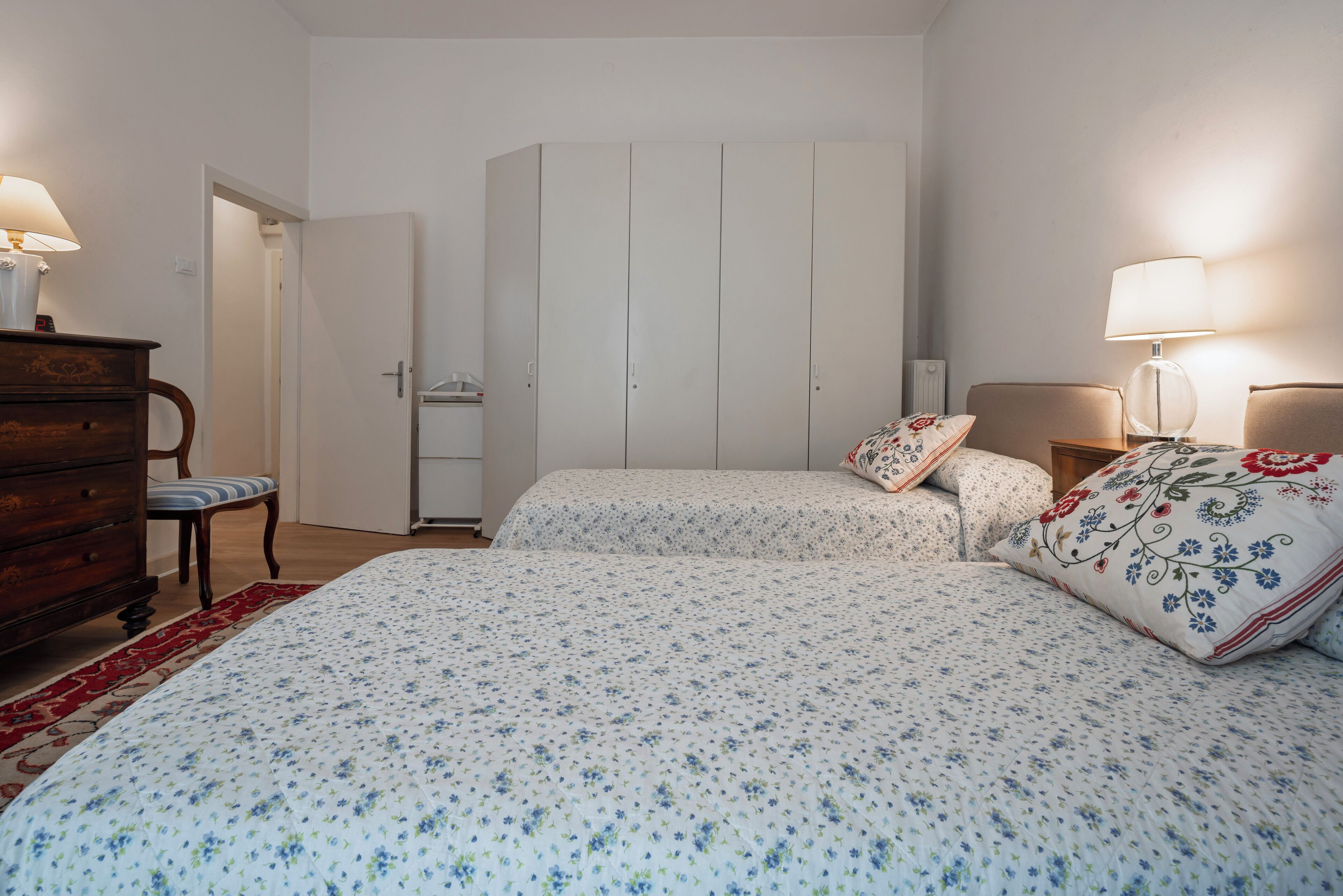 A bedroom with two beds, a wardrobe, a dresser, and a chair.