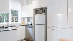 Una cocina moderna con armarios blancos, microondas integrado y refrigerador.