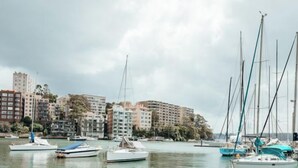 Una marina con varios veleros amarrados, rodeada de edificios de varios pisos.