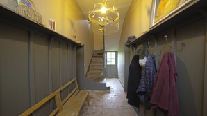 A narrow hallway with a wooden bench, a staircase, and a coat rack with several jackets. - Country house in town. (Angoulême)