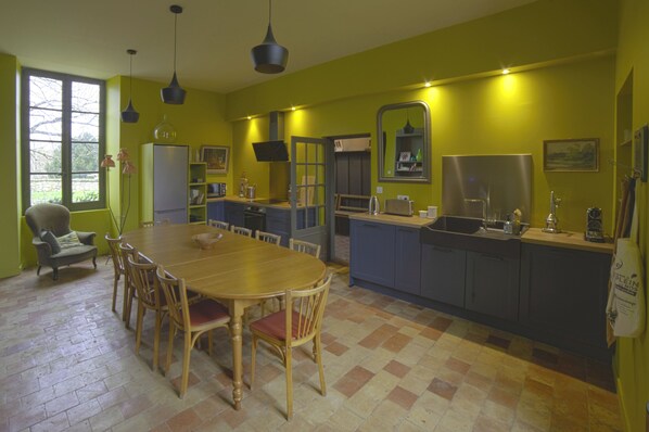 A kitchen with a dining table and chairs, a refrigerator, and a sink. - Country house in town. (Angoulême)