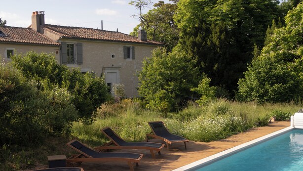 A poolside area with lounge chairs and a house in the background. - Country house in town. (Angoulême)