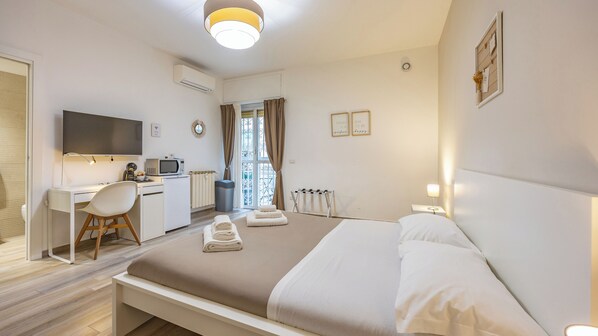A modern hotel room with a bed, desk, and kitchenette. - Ostiense Flat&Rooms by Rentbeat (Rome)