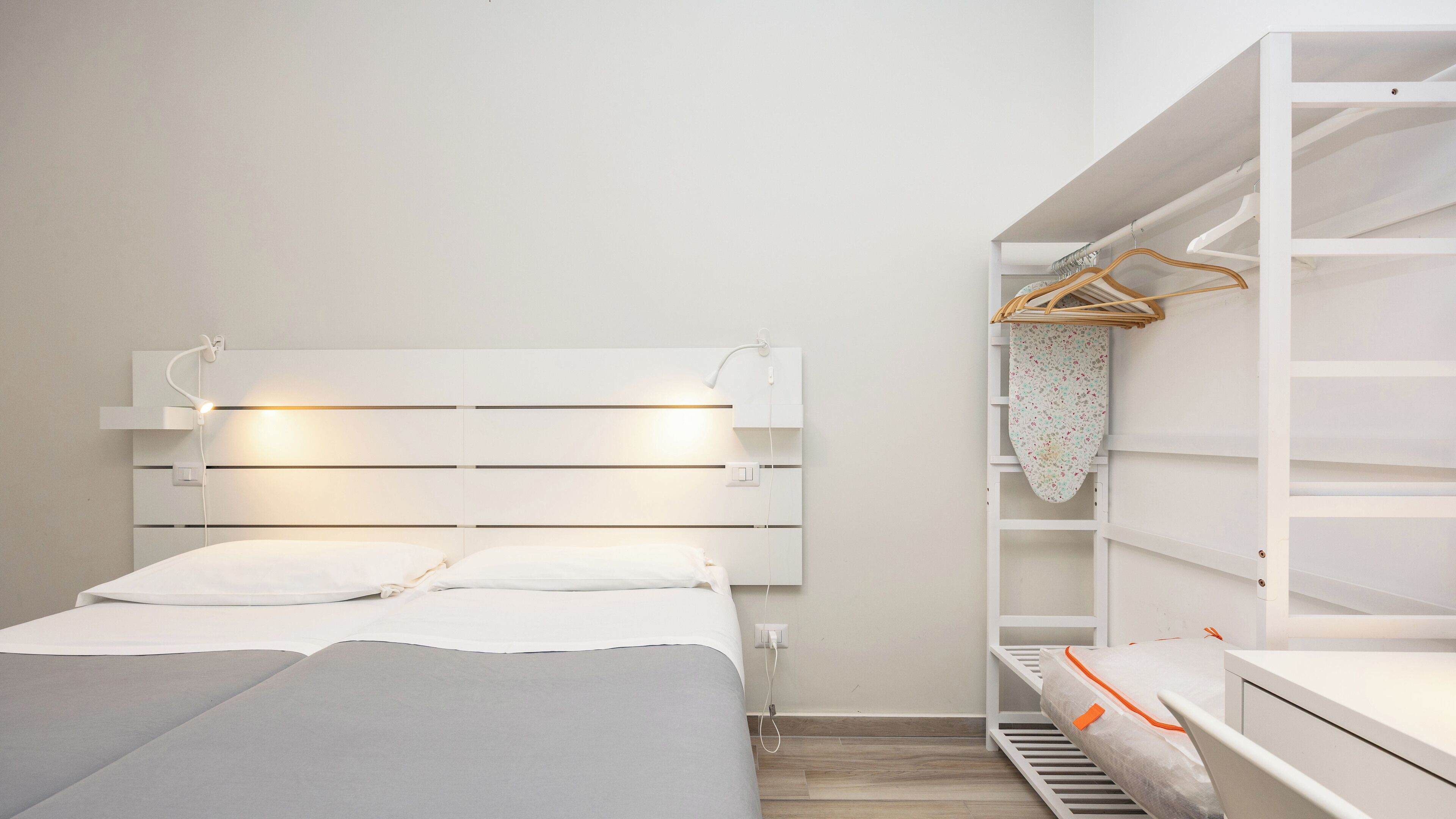 Ein Schlafzimmer mit Bett, Nachttischen, einem Kleiderschrank und einer Kleiderstange.