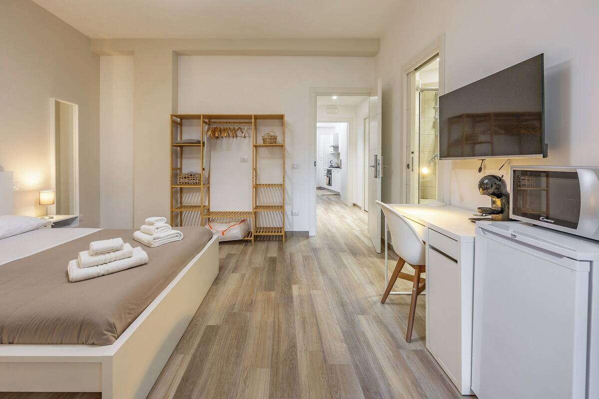 A hotel room with a bed, a desk, a microwave, and a wardrobe.