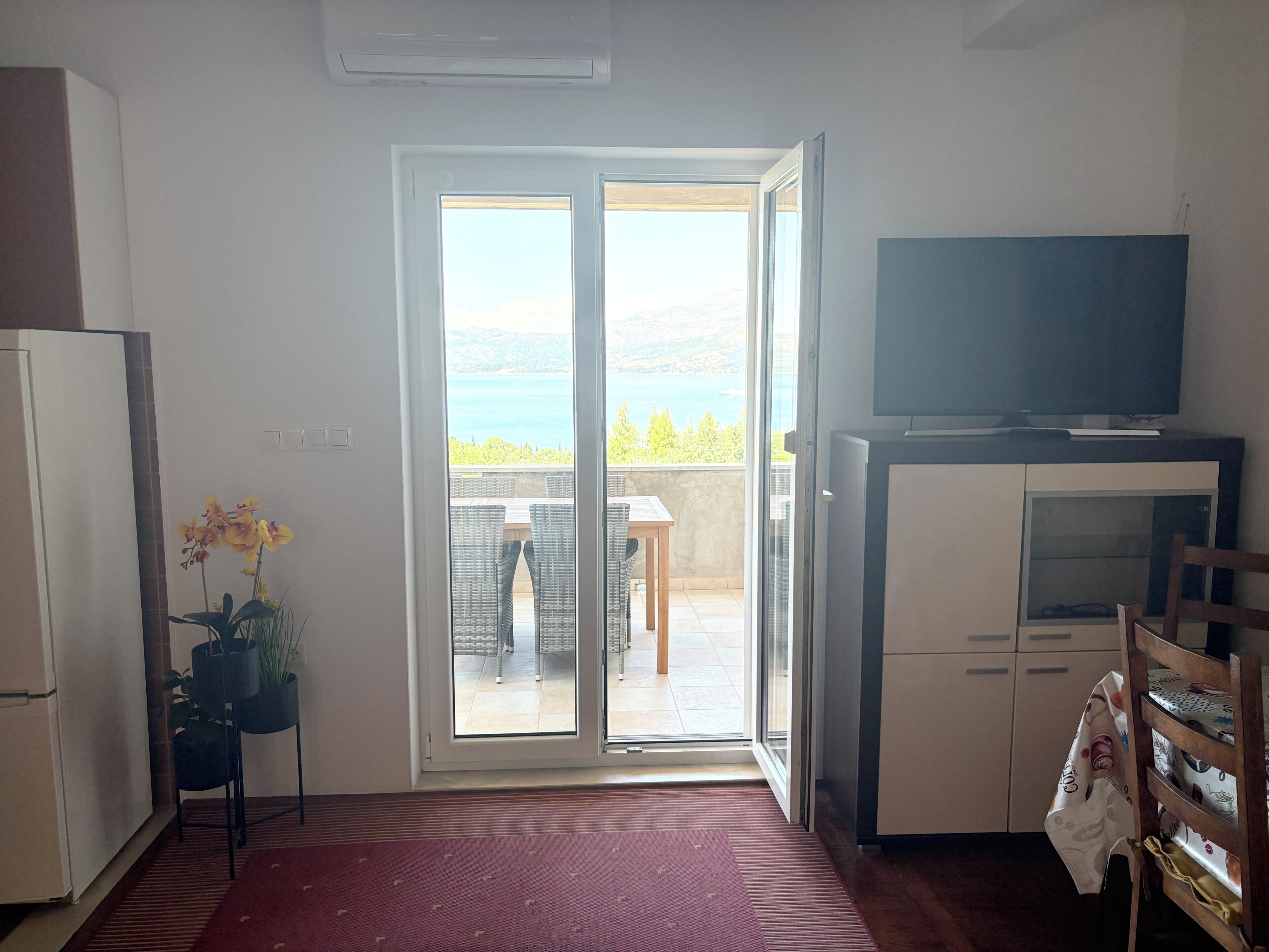 Una cocina con puerta corrediza de vidrio que da a un balcón con vista al mar.