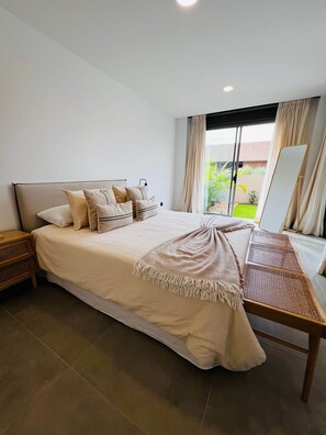 Een slaapkamer met een groot bed, een nachtkastje, een spiegel en uitzicht op de omgeving.