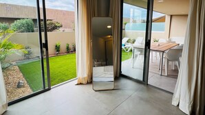 A modern hotel room with large sliding glass doors leading to a balcony, a flat-screen TV, and a small seating area with a table and chairs. - La Tejita Amor by Be Happy Sotavento Suites (La Tejita)