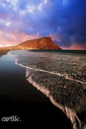 Une plage avec une montagne en arrière-plan et une eau calme.