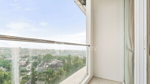 A balcony with a glass railing overlooking a residential area. - Astrum by Kozystay - Ciumbuleuit (Bandung)