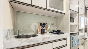 A modern kitchen with a sink, a microwave, and a refrigerator. - Astrum by Kozystay - Ciumbuleuit (Bandung)