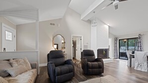 A spacious living room with a sofa, two armchairs, a coffee table, and a fireplace.