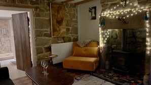 Una sala de estar acogedora con una pared de piedra, chimenea, sofá, una mesa de centro y una alfombra.