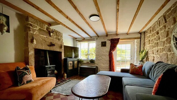 Una sala de estar acogedora con chimenea de piedra, un sofá, un televisor y una mesita.