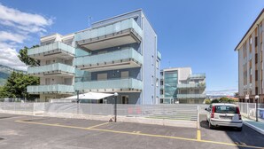 Un edificio de varios pisos con balcones, un estacionamiento y un coche estacionado al frente.
