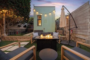Une terrasse avec un foyer, du mobilier d’extérieur et des guirlandes lumineuses.