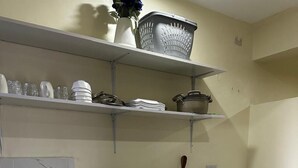 A modern kitchen with white cabinets, a black stove, a microwave, and a sink. - Girrafe Apartments (Dar es Salaam)