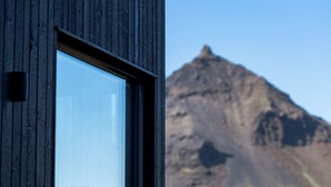 A window with a view of a mountain. - Peninsula Suites (Hellnar)
