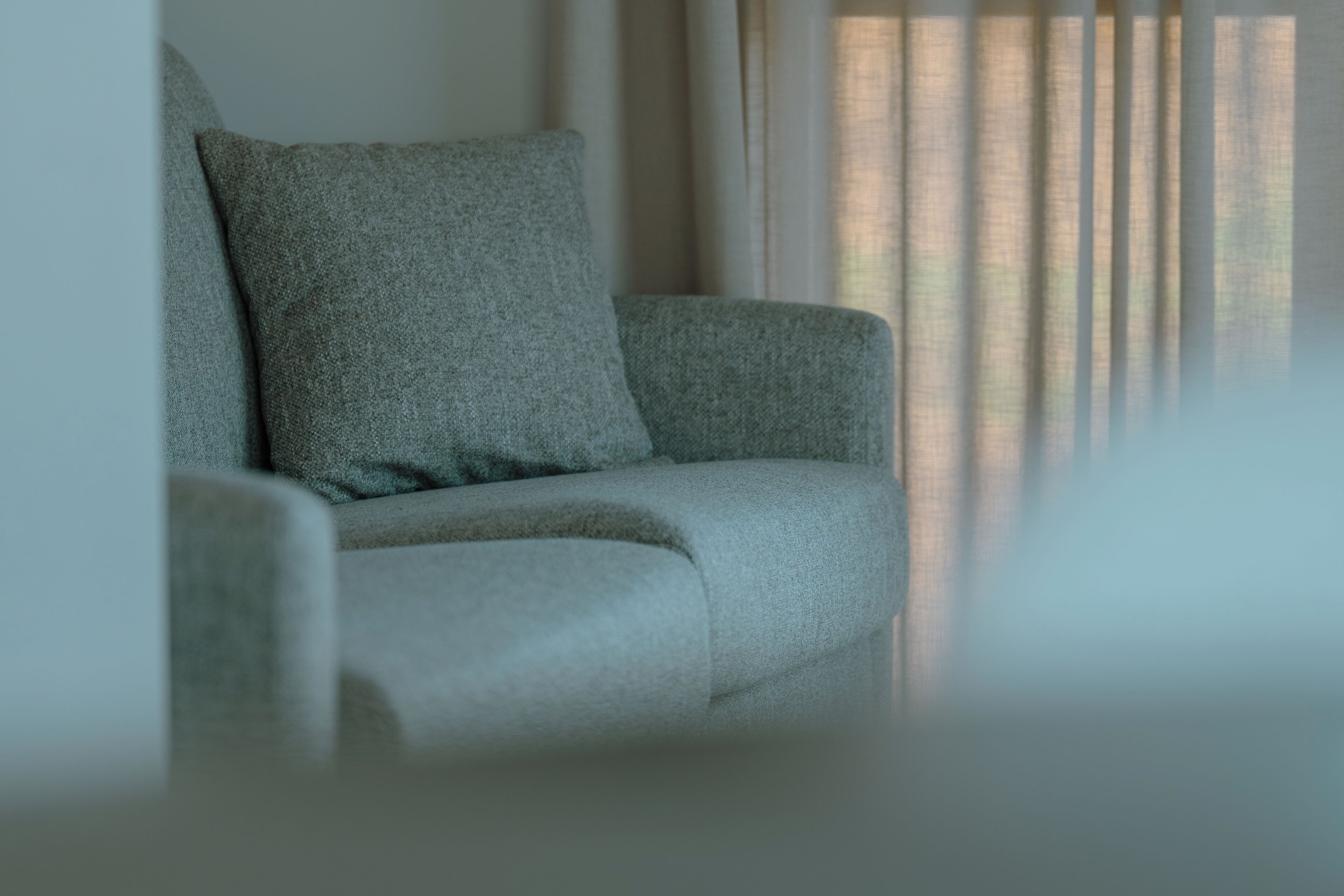 A modern living room with a grey sofa and a large window with curtains.