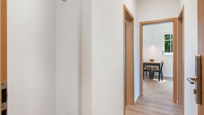 Ein Korridor mit Holzboden, der zu einem Essbereich mit Tisch und Stühlen führt.