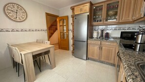 A kitchen with wooden cabinets, a stainless steel refrigerator, a microwave, and a dining table with chairs. - Trasgu House for 6 people in Infiesto (infiesto, piloña)