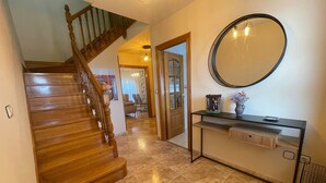 A wooden staircase leading to a living area with a round mirror on the wall and a console table with a vase. - Trasgu House for 6 people in Infiesto (infiesto, piloña)