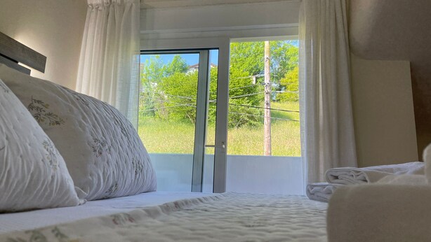 A bedroom with a bed, white curtains, and a view of greenery outside. - Trasgu House for 6 people in Infiesto (infiesto, piloña)