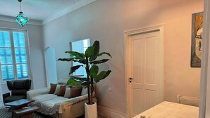 En hyggelig stue med en sofa, et sofabord, en potteplante og et mønstret tæppe.