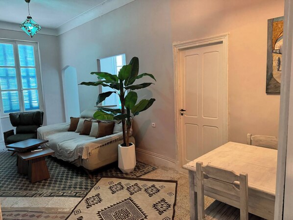 Una sala de estar acogedora con un sofá, una mesa de centro, una planta en maceta y una alfombra estampada.