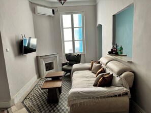 A living room with a sofa, a TV, a fireplace, and a window. - Cozy Luxury Apartment in the Heart of Tunis (Tunis)