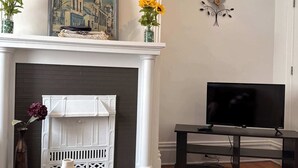 Olohuone, jossa on takka, taulu, televisio ja kuviollinen matto.