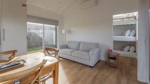 Ein Zimmer mit einer weißen Couch, einem Holzesstisch und einem Etagenbett mit Kissen.