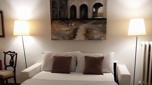 Un dormitorio con una cama grande, dos lámparas de noche, un cuadro en la pared y una silla.