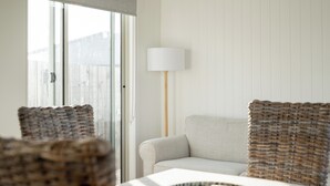 A room with a sofa, a lamp, and wicker furniture.