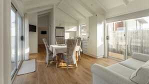 A spacious dining area with a table and wicker chairs, a kitchen with white cabinets, and a sliding glass door leading to an outdoor area.