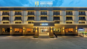 A modern hotel with a prominent entrance, multiple balconies, and a well-lit facade.