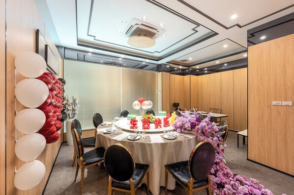 A conference room with a round table, chairs, and a cake with red and white balloons.