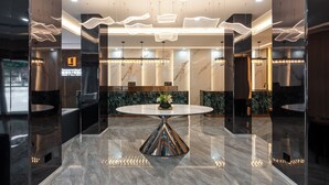 A modern lobby with a marble floor, a central round table, and contemporary lighting fixtures.