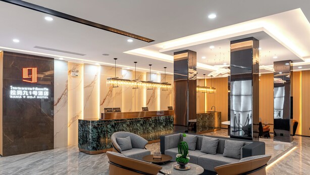 A modern hotel lobby with marble flooring, a reception desk, and a seating area with sofas and a coffee table.