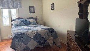 Una camera da letto con un letto, una ventola a soffitto, una cassettiera, un televisore e una finestra con vista.